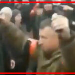 Russian invader holds up a grenade in each hand as he walks among Ukrainians demanding they surrender